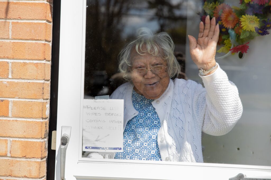 Older woman waving from home during a Meals on Wheels check-in