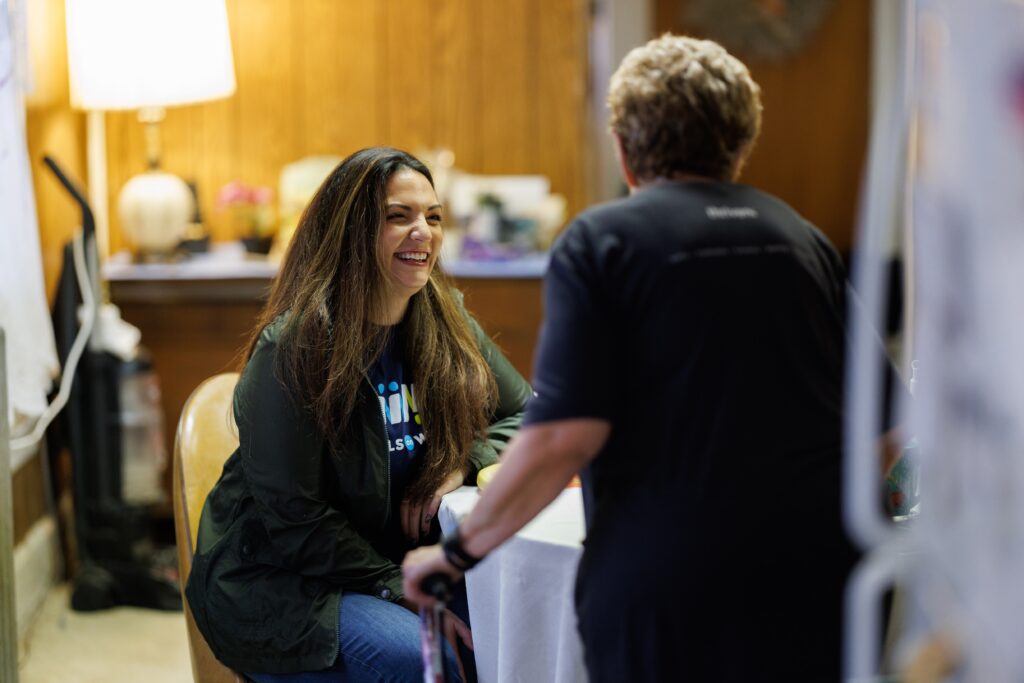 A Meals on Wheels volunteer helps an older woman in her kitchen