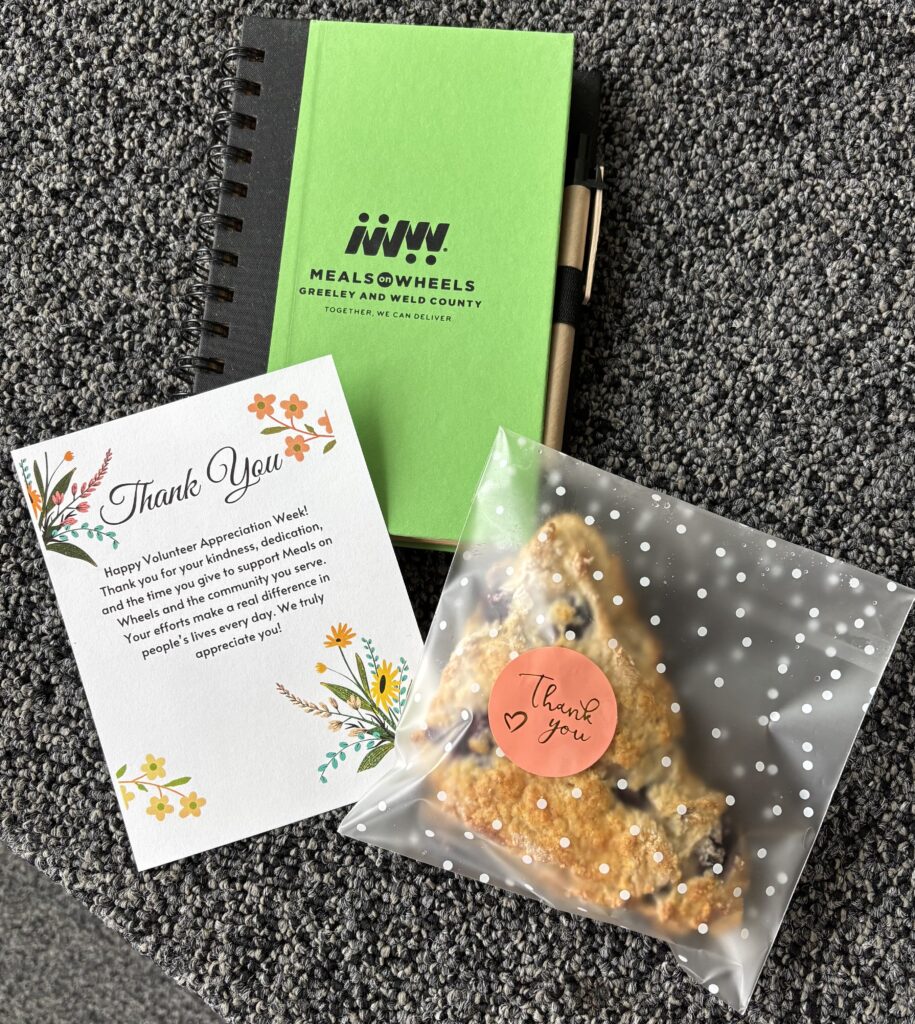 Meals on Wheels of Greeley and Weld County Volunteer Appreciation Week gifts, including a thank you card, branded notebook, pen, and breakfast scone for volunteers.