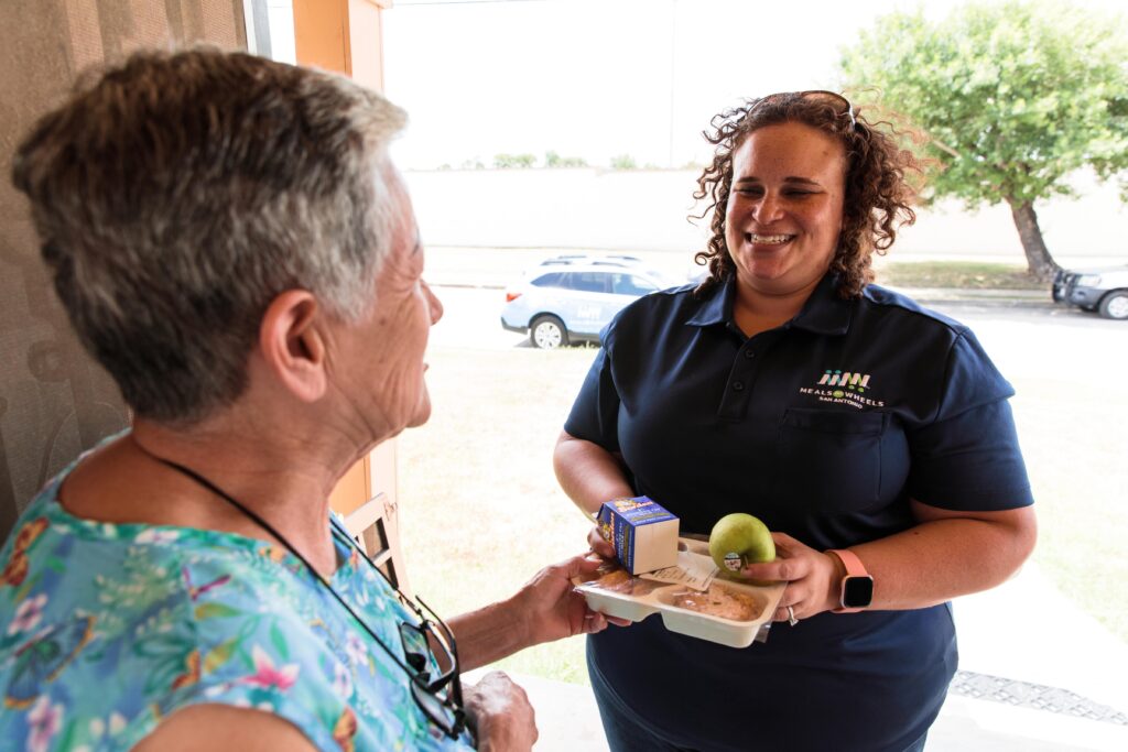 Smiling Meals on Wheels volunteer delivers a hot meal and a friendly check0in at a client's door